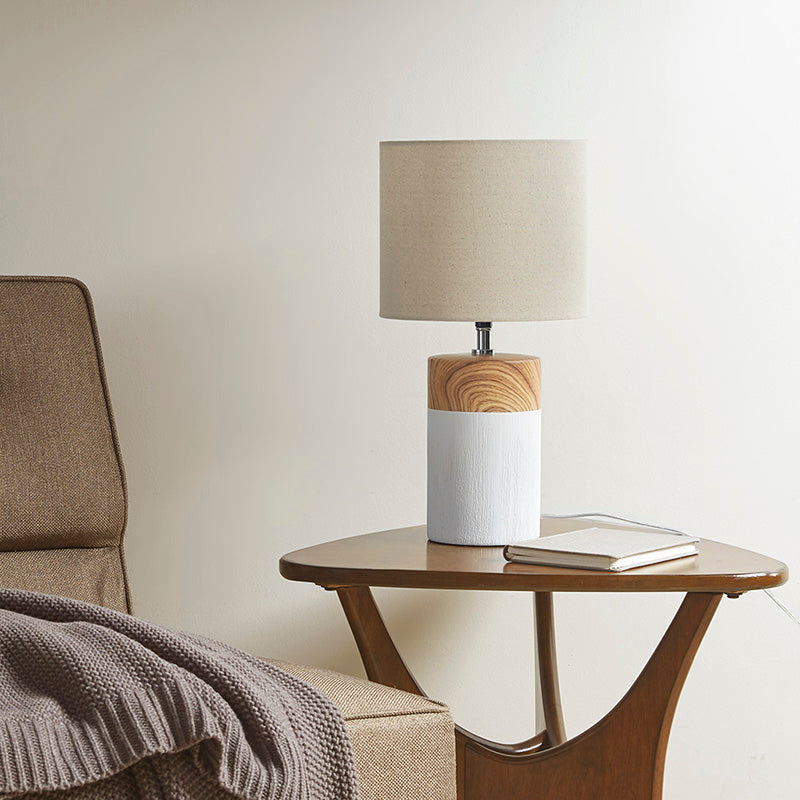 a white ceramic table lamp placed on a side table in a living area