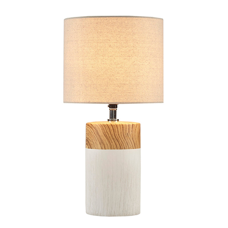 an illuminated white ceramic table lamp in a white background