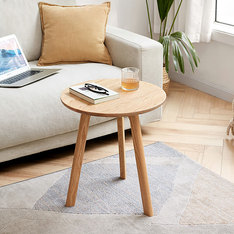 a natural round wood end table in a chic modern living room