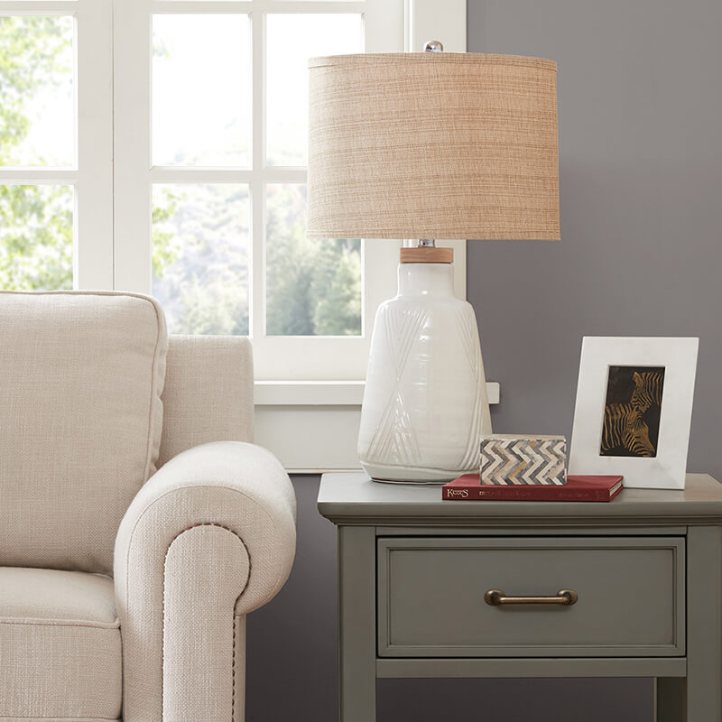 Ceramic table lamp with white base and natural shade on an end table