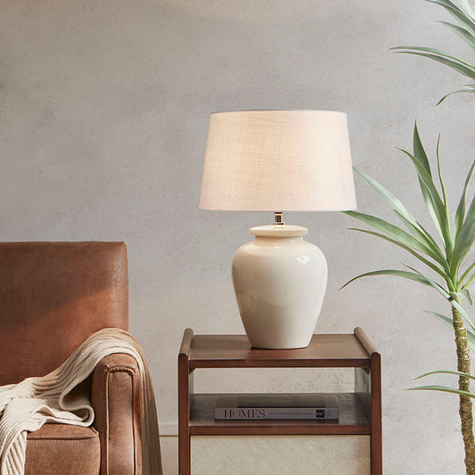 a modern cream ceramic table lamp with drum-shaped shade in a stylish living area