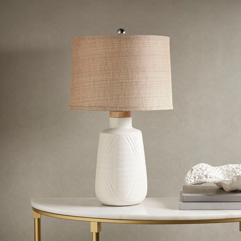 Ceramic table lamp with white base and natural shade on a side table