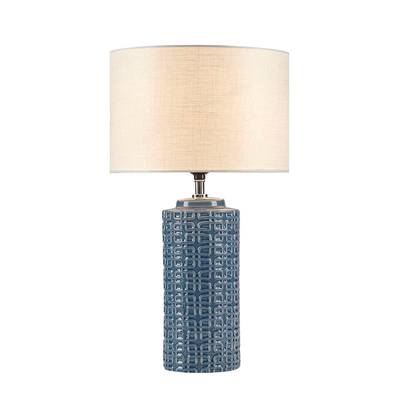 Ceramic table lamp with blue patterned cylinder and white drum shade turned on