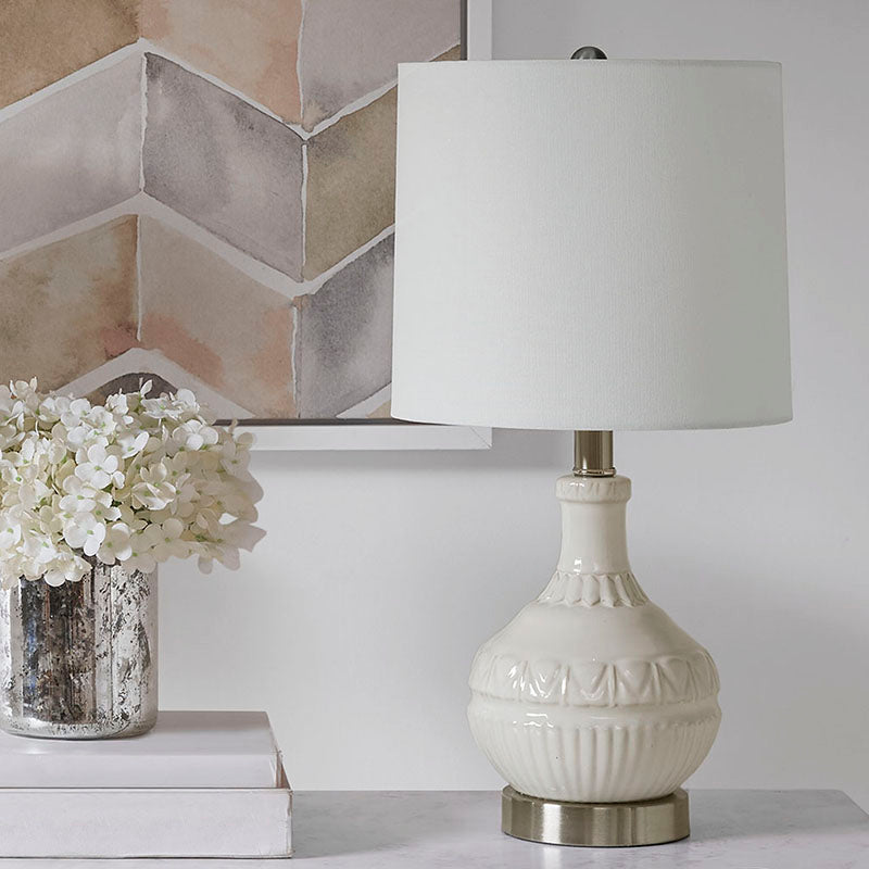 White ceramic table lamp with white lamp shade and patterned base turned off