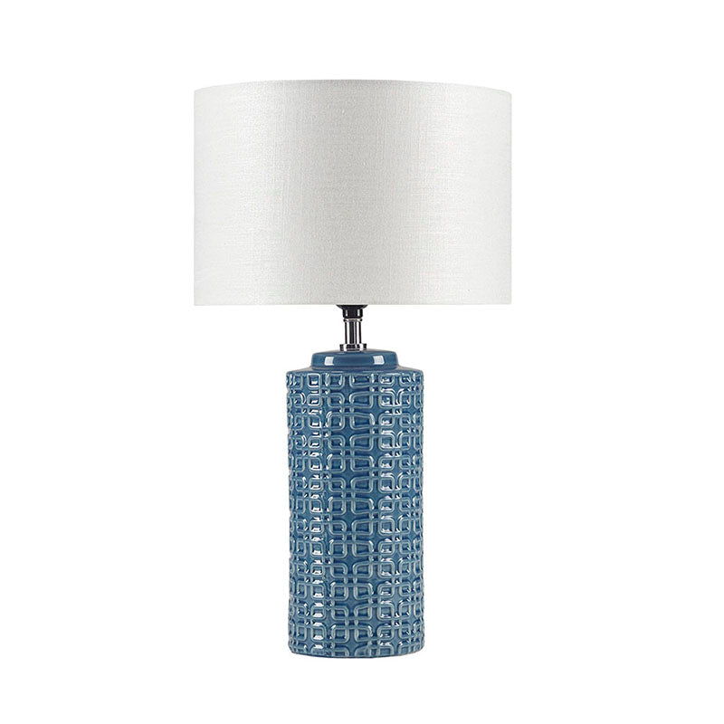 Ceramic table lamp with blue patterned cylinder and white drum shade turned on