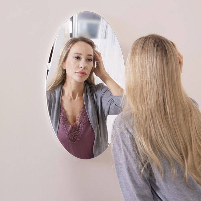 a woman looking at her reflection in the mirror'