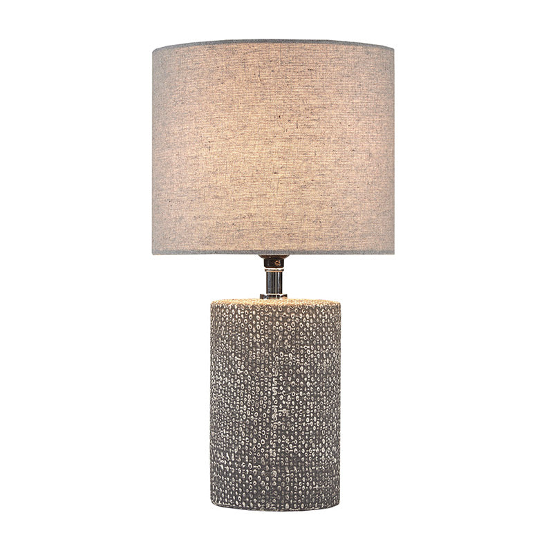 Full view of Ceramic table lamp with embossed base turned on