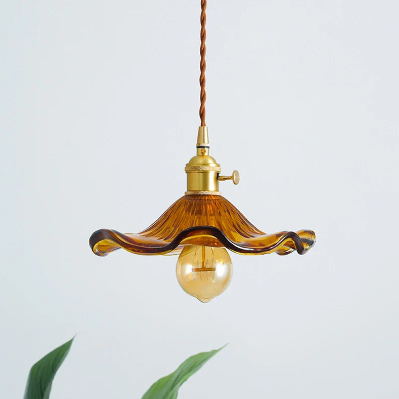 Ceiling mounted amber glass pendant light showing, amber glass floral lamp shade, light bulb, and brass lamp holder