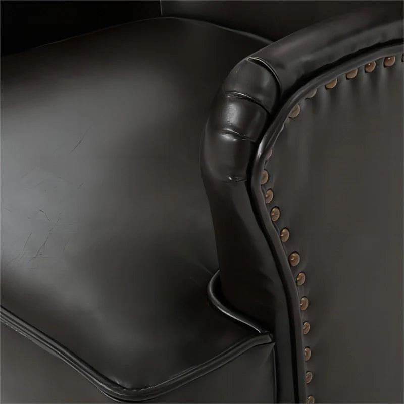 Image of brown leather accent chair highlighting nailhead design of armrest