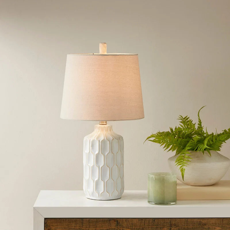  A turned on Ivory and white ceramic table lamp with contoured base on a side board