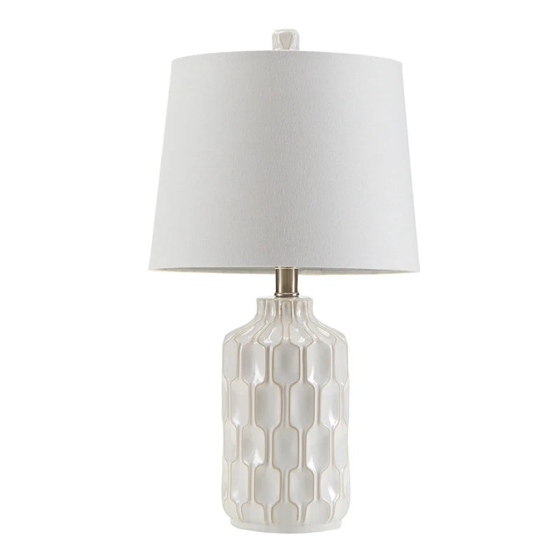 Full view of a turned off Ivory and white ceramic table lamp with contoured base 