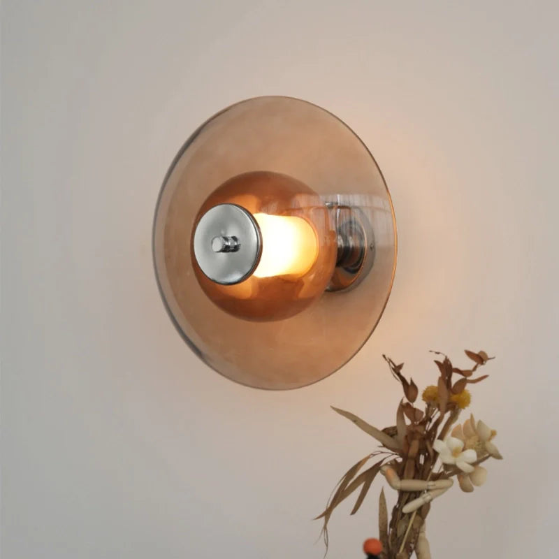 a plug in wall light sconce with a glass shade in amber