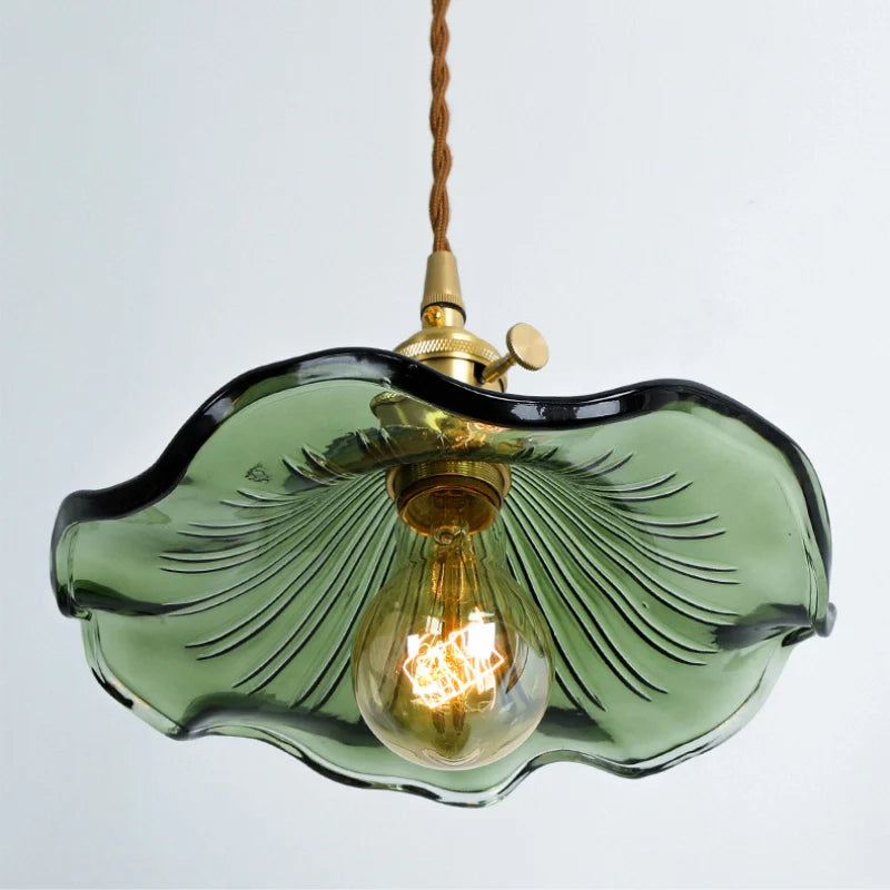 Ceiling mounted green glass pendant light showing illuminated bulb, floral lamp shade and brass lamp holder