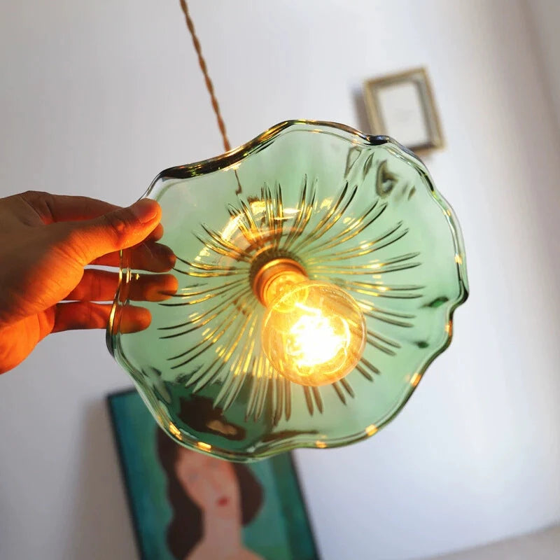 Upclose view of the green glass pendant light showing, green glass floral lamp shade and illuminating Light bulb