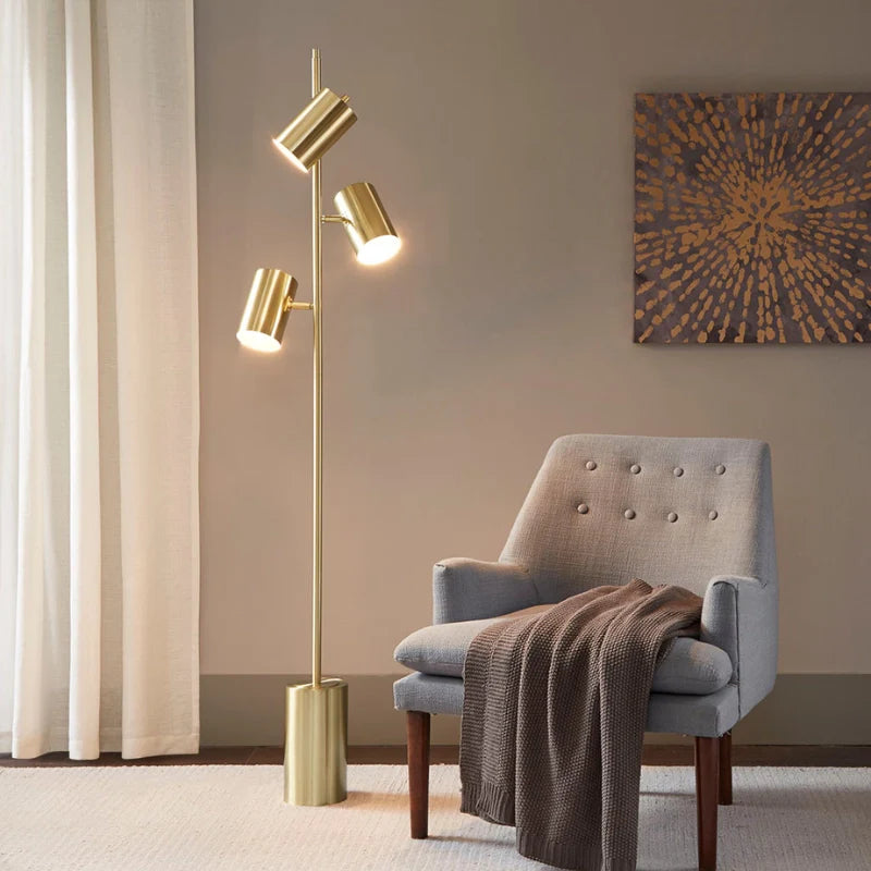 Modern Gold Floor Lamb with lights turned on in a modern space by a lounge chair