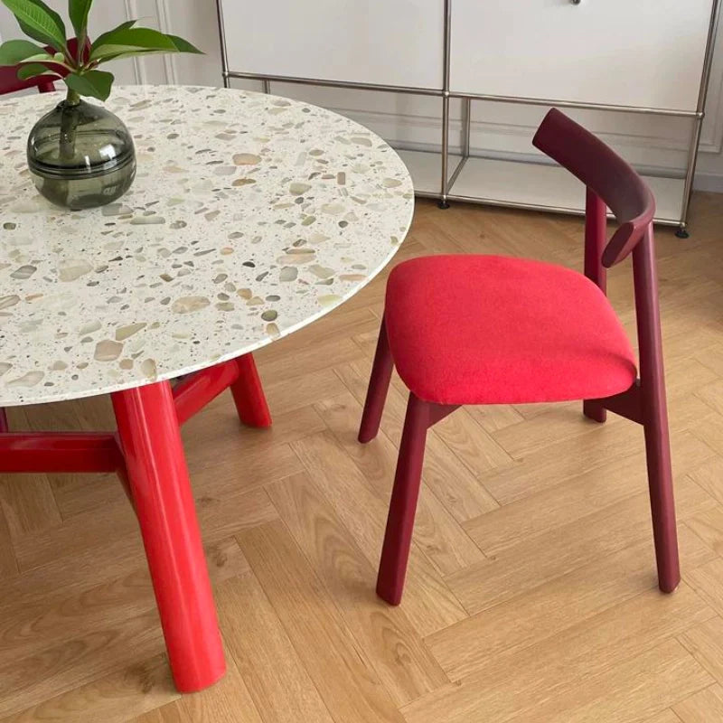 a wood dining table with a round tables top and a red base