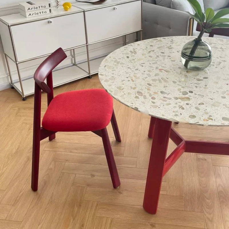 a solid wood dining room table with sintered stone top and a red dining chair