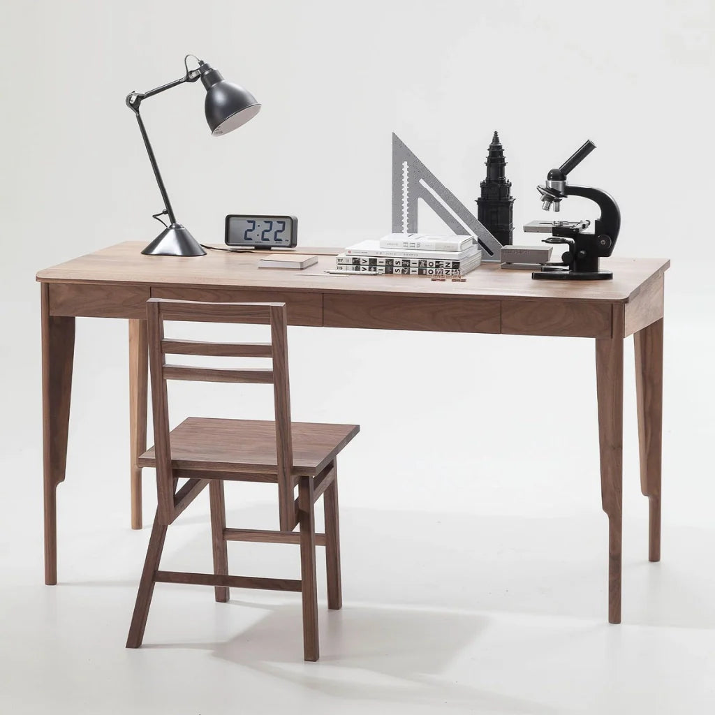 A large wooden desk with drawers, paired with a matching chair, and showcasing some office essentials on it tabletop.