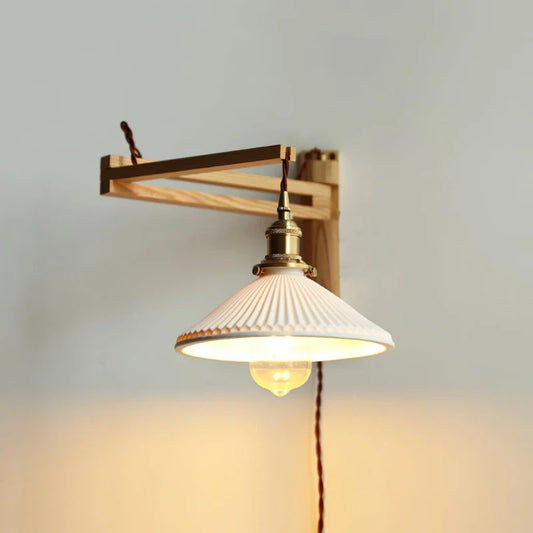 A turned on plug in Wall Lamp with Retractable Arm and ceramic lamp shade in Natural and White