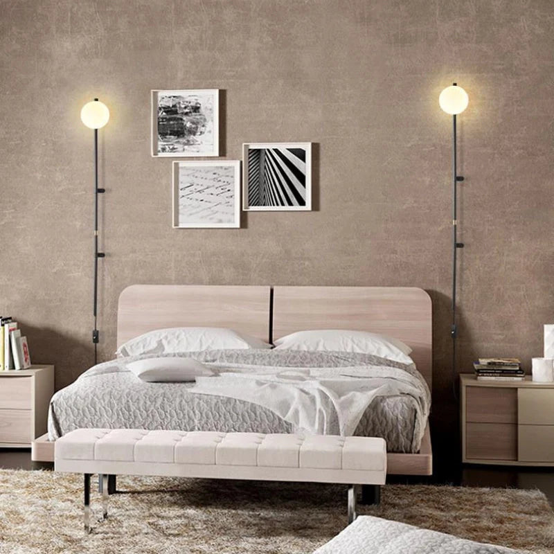 Modern Plug In Wall Light Fixture with LED Globe shade in a set of 2 illuminating a modern bedroom setting