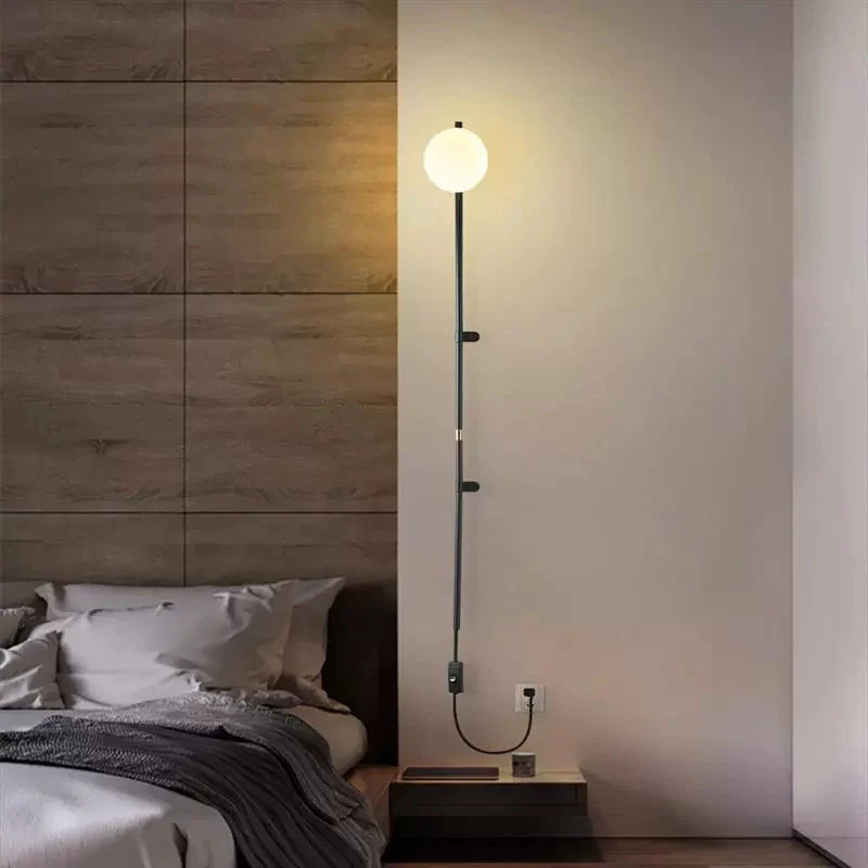 Modern Plug In Wall Light Fixture with Glass Globe shade in a cozy bedroom setting