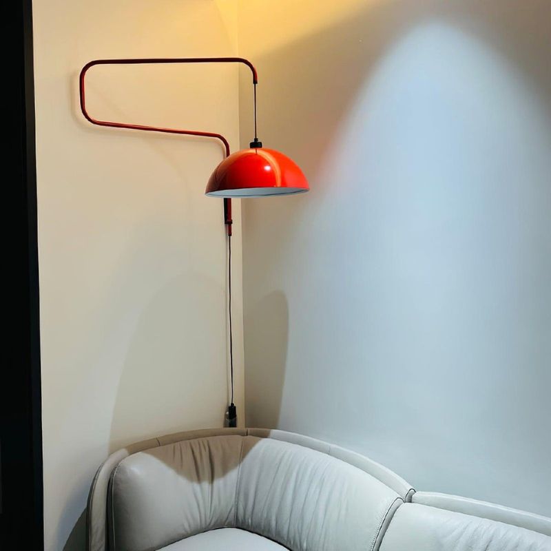 Red Plug in Wall Light with dome shade over a cozy living room setitng