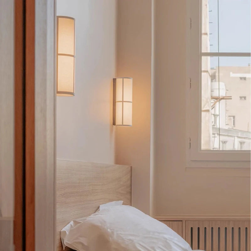 A pair of turned on plug in wall sconce installed by the bedside