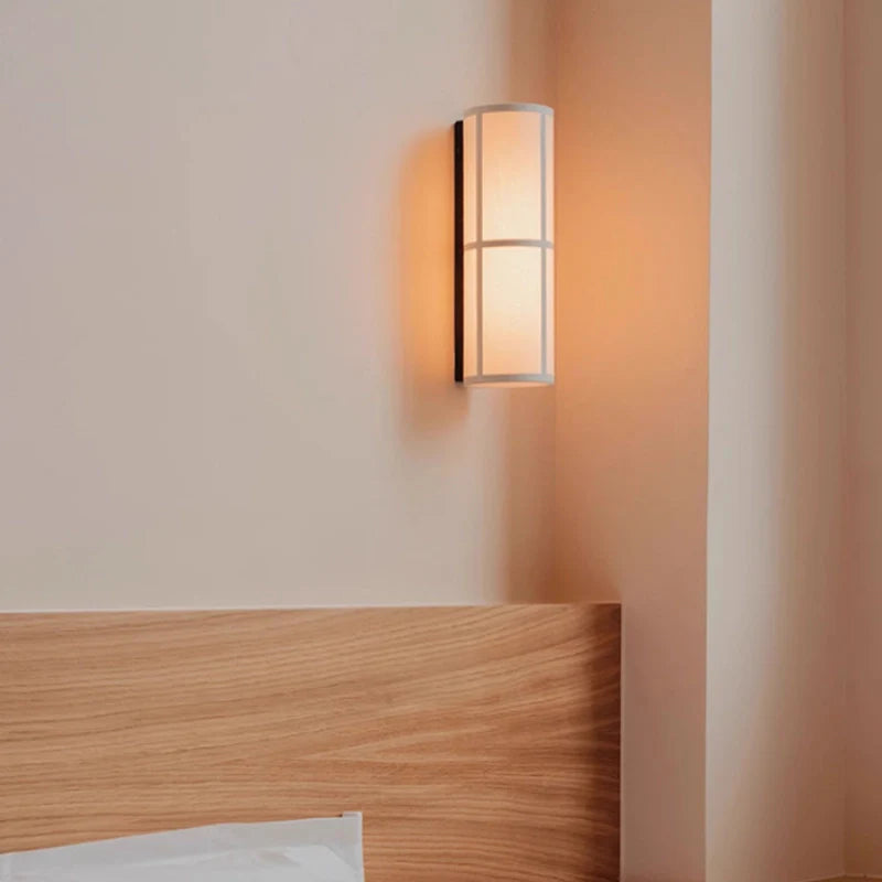 Hardwired Variant of cylinder fabric wall sconce installed by the bedside