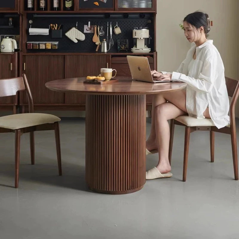 A Wooden Pedestal Dining Table in a Modern Dining Area in Rich Walnut Color, Providing a Stable Surface for remote work, and serving Snacks.