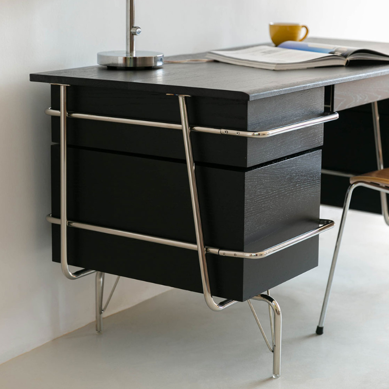 Black wood office desk highlighting its side drawer and unique chrome frame