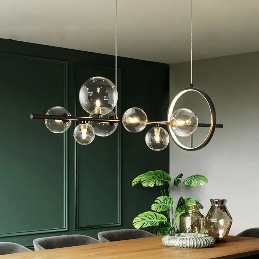 A modern linear kitchen island chandelier with glass globe shade above a chic dining table