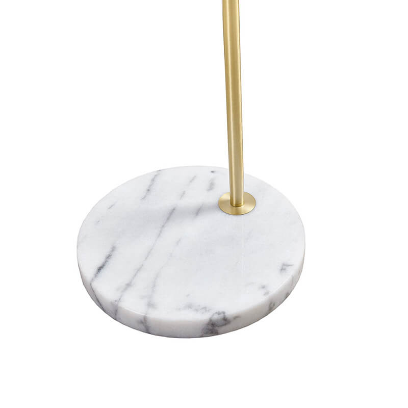 Up close image of the modern gold floor lamp high;ighting its white marble base