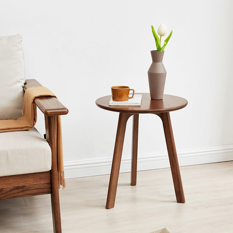 a walnut round wood end table in a chic modern living room