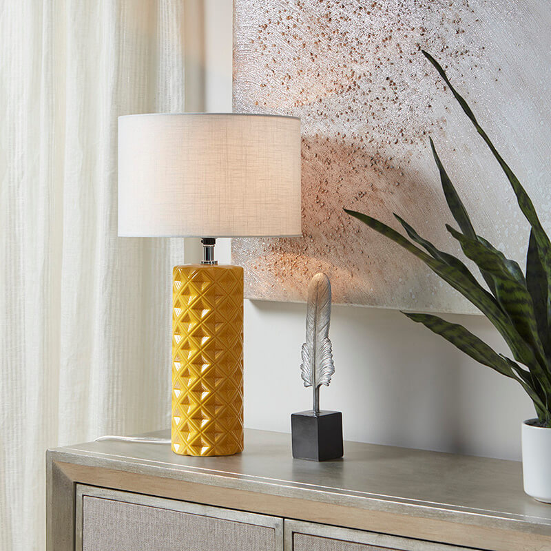 a yellow geometric ceramic table lamp with fabric shade and patterned cylinder base